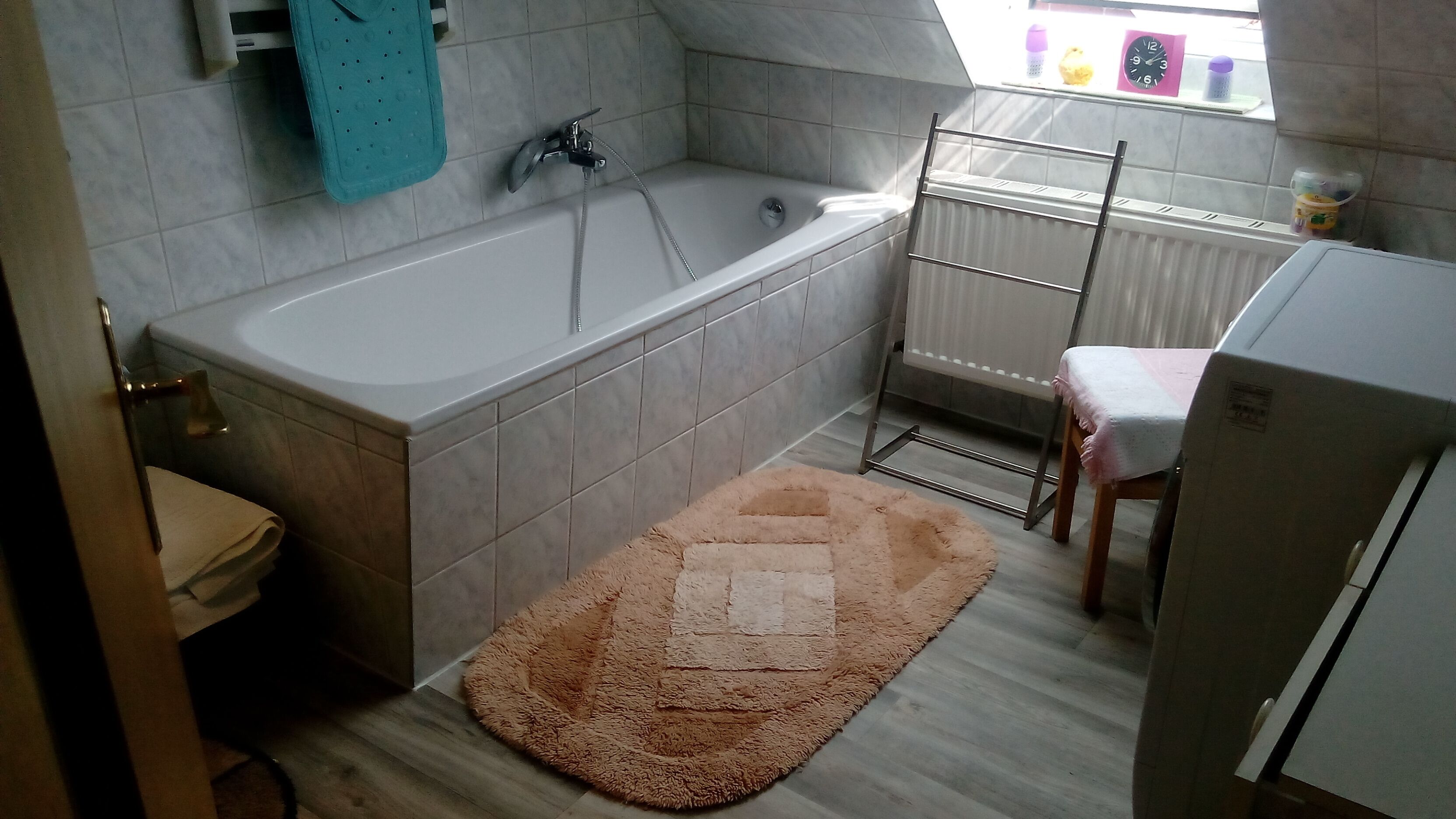 Ein Badezimmer mit Badewanne, Toilette, Waschbecken, einem Fenster mit Blick und einem Heizkörper.