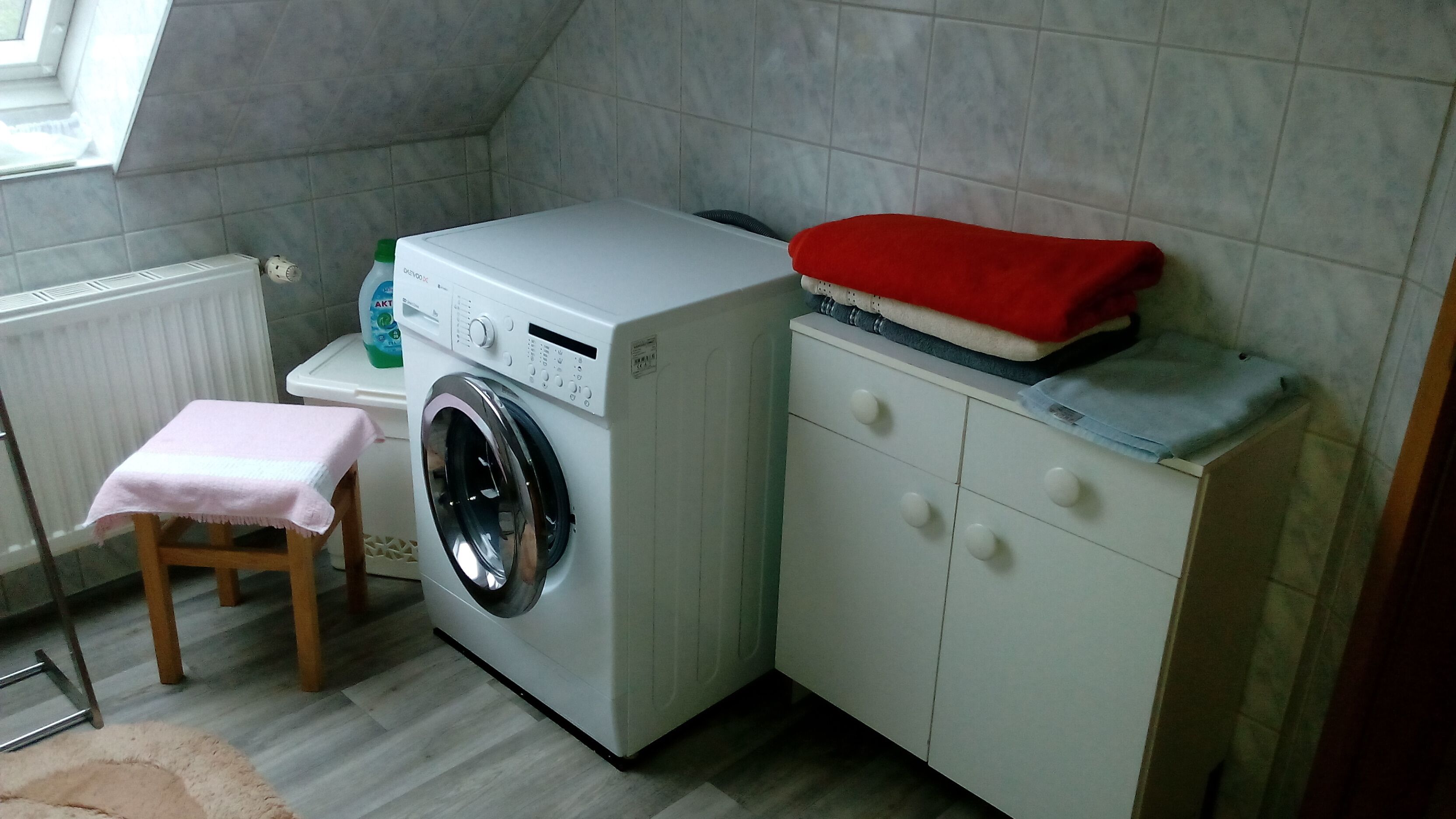 Un espace buanderie comprenant un lave-linge, un étendoir et une petite table avec une serviette.