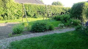 Un jardín con un columpio de madera y una escalera.