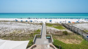 A beach with a wooden boardwalk leading to the water, sandy beach, and beach umbrellas. - Inn at Crystal Beach 305 * Gulf Front with Beach Chair Set. Onsite dining! (Destin)