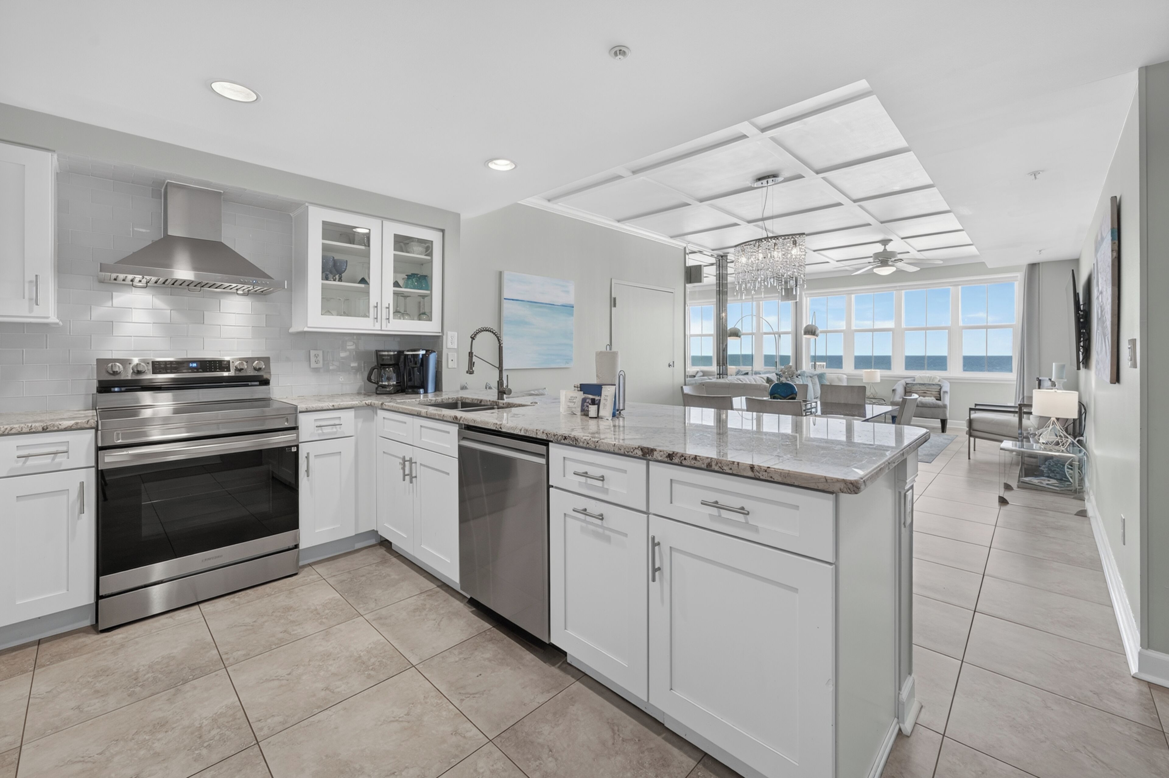 A modern kitchen with stainless steel appliances, white cabinetry, and a large island.