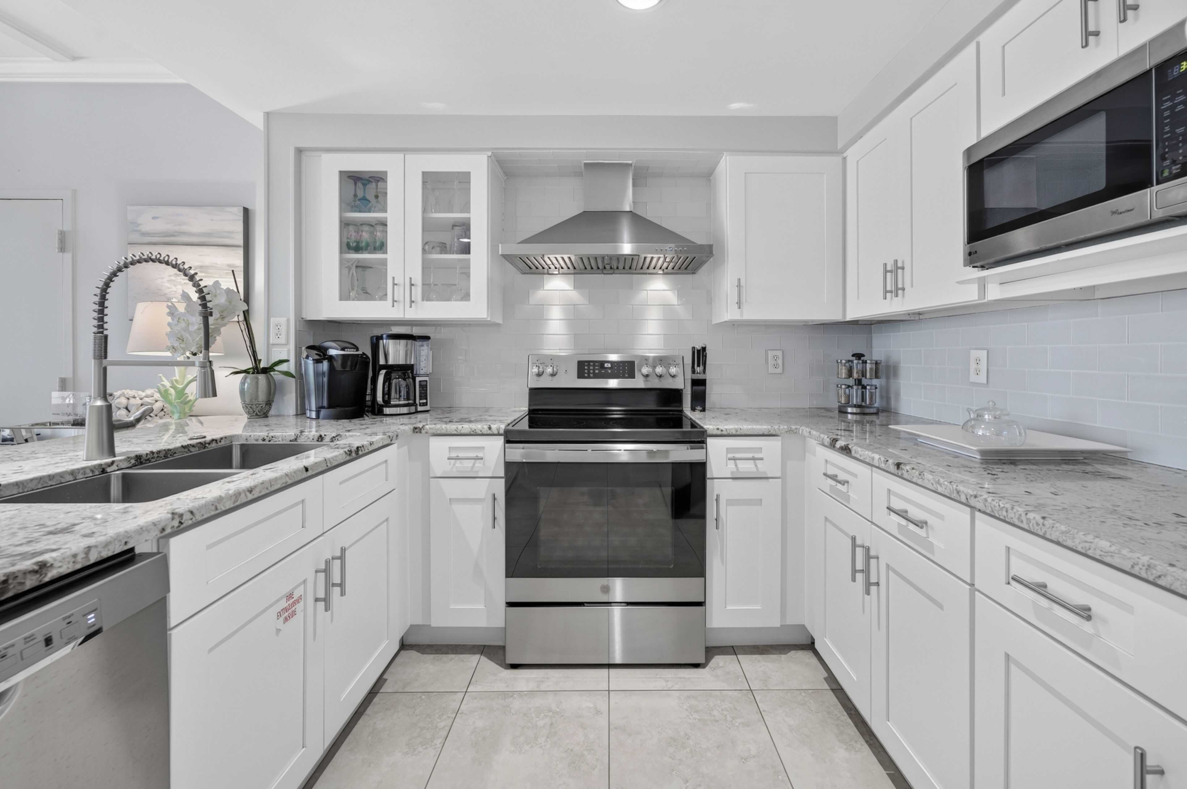A modern kitchen with white cabinetry, stainless steel appliances, and a granite countertop.