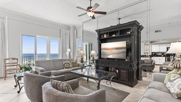 A spacious living room with a large flat-screen TV, comfortable seating, and a balcony with a view. - Inn at Crystal Beach 210a * Gulf Front with Beach Chair Set. Onsite dining! (Destin)
