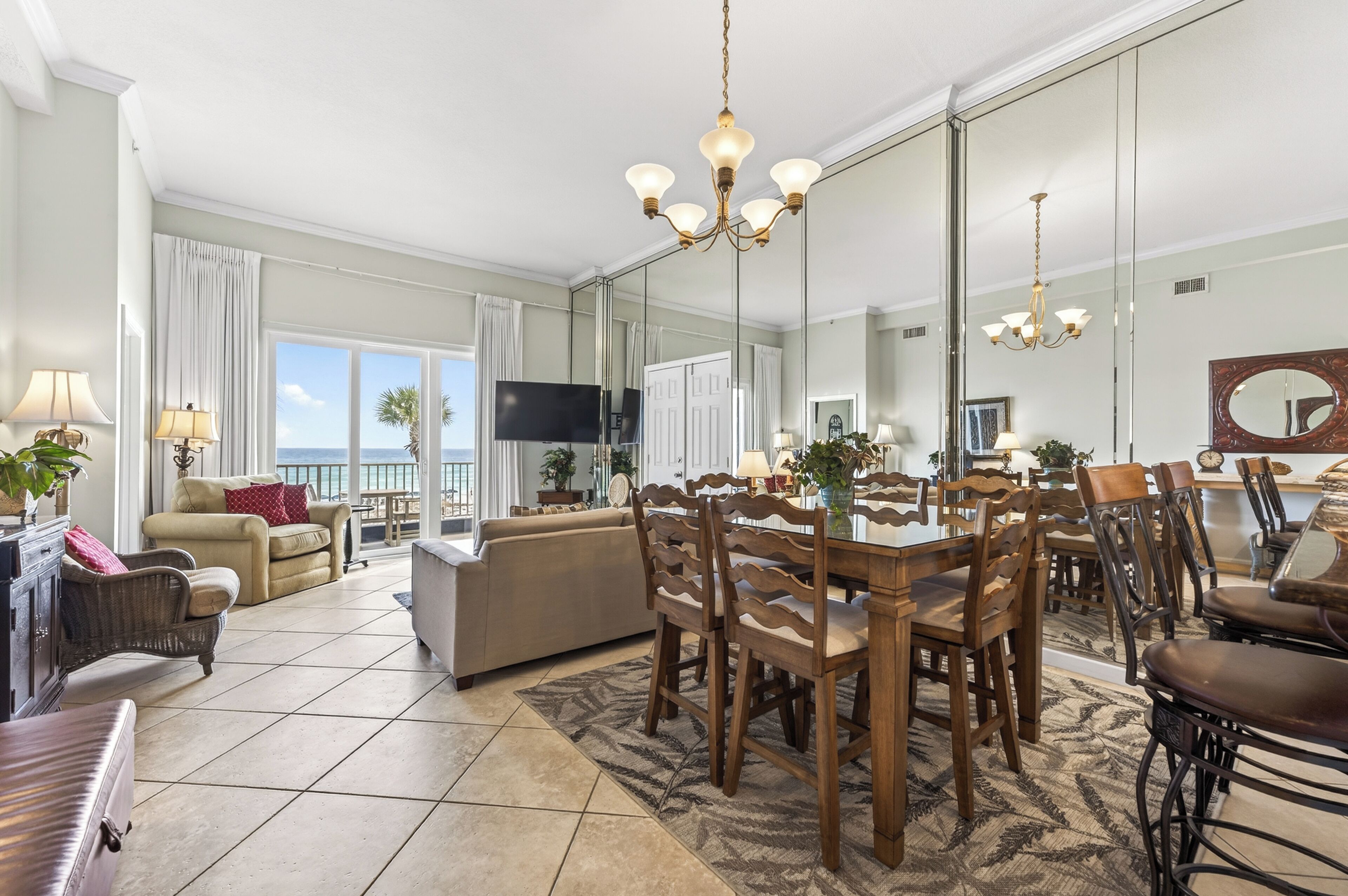 A spacious living room with a large dining table, multiple chairs, a sofa, and a television.