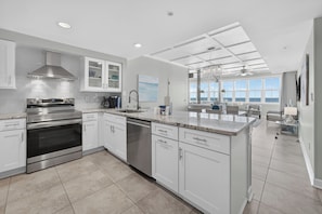 A modern kitchen with stainless steel appliances, white cabinetry, and a large island.