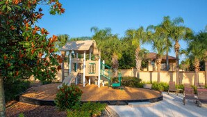 A playground with a slide and climbing structures, surrounded by palm trees and a paved area with benches. - Sept. Special 6th Night Free in Waterpark Resort & Spa, Golf, minutes to Disney (Davenport)