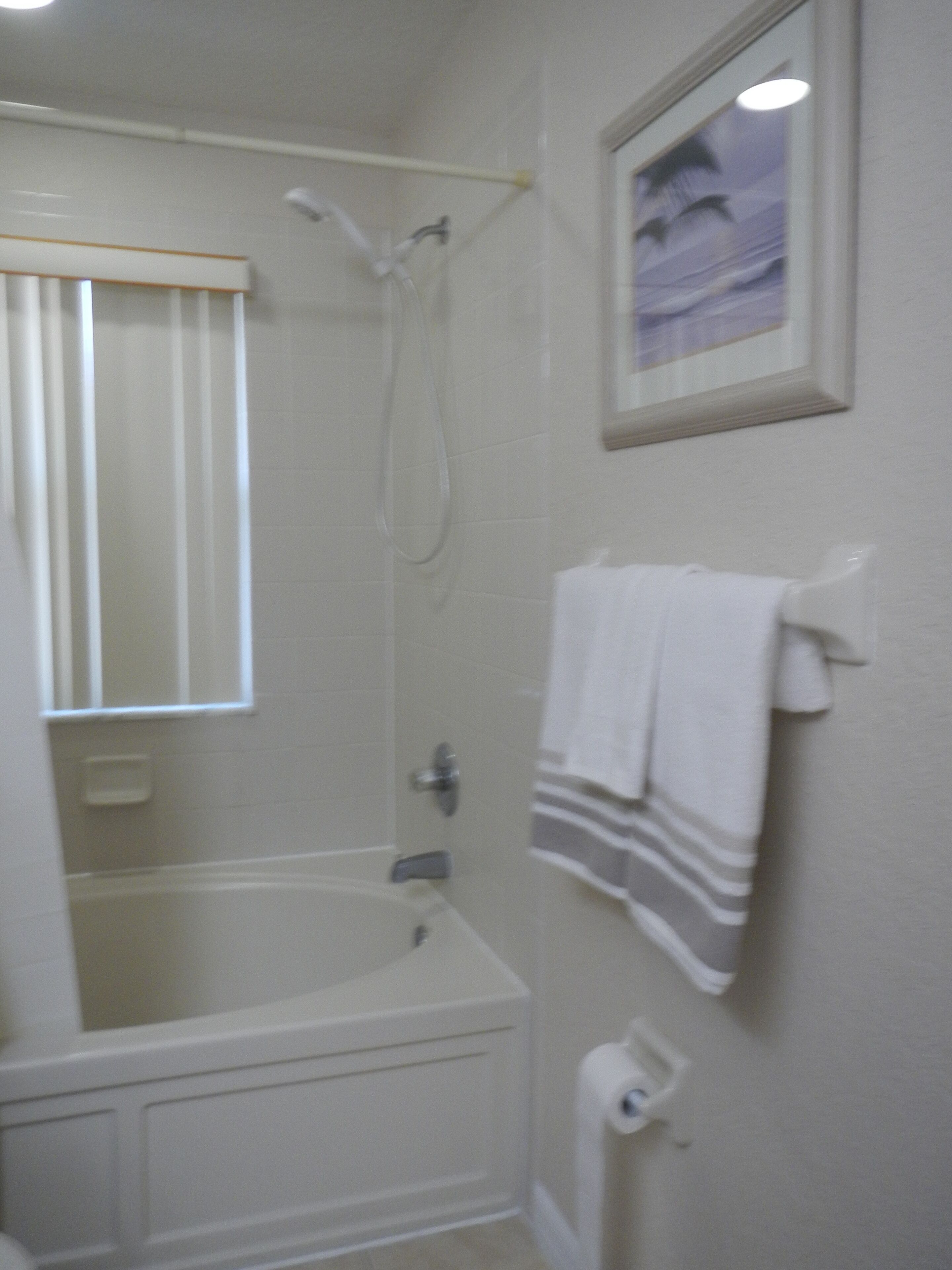 A bathroom with a bathtub, a shower, a toilet, and a towel rack with towels.