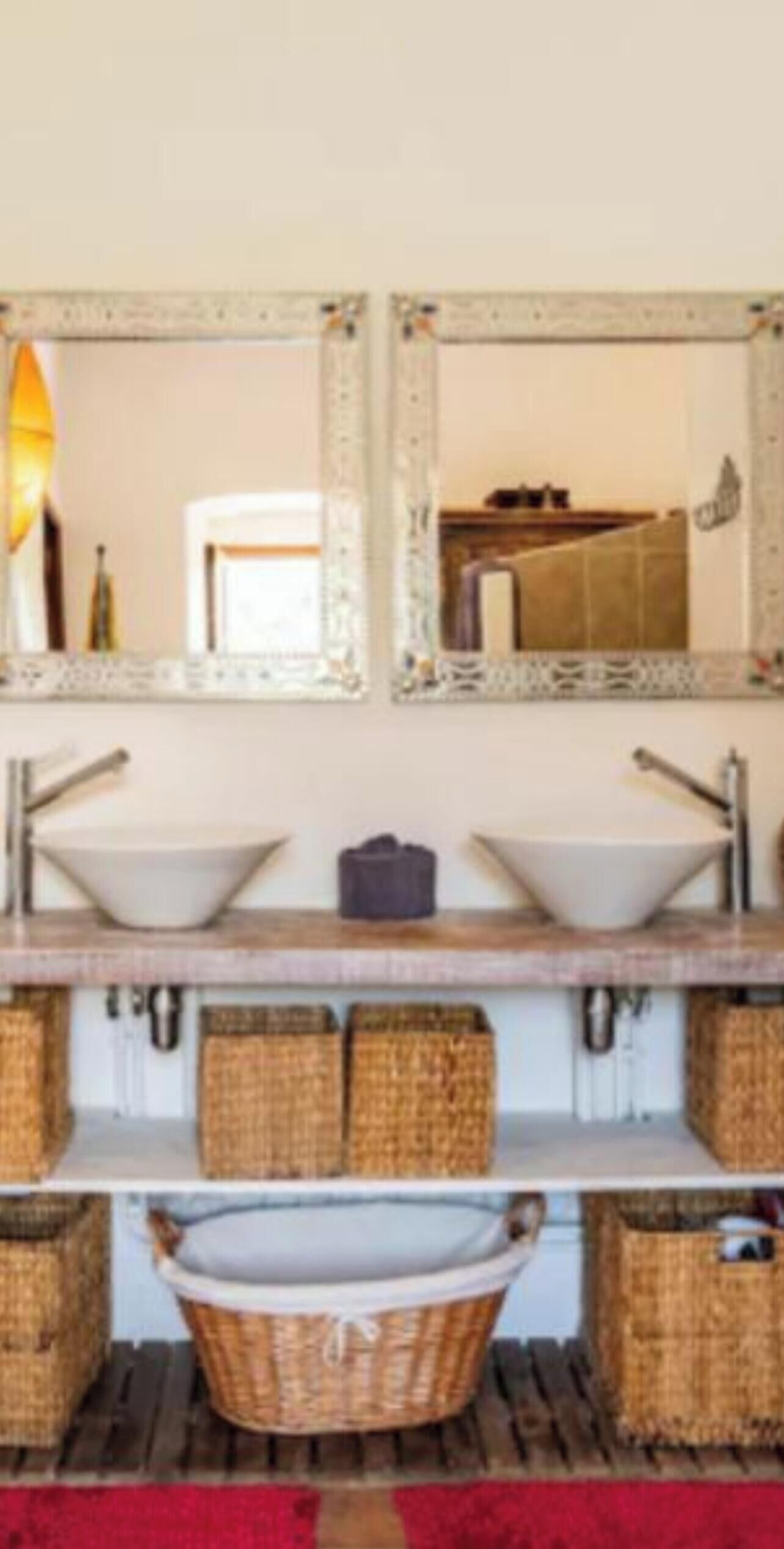 A bathroom with two sinks, a mirror, and wicker baskets.