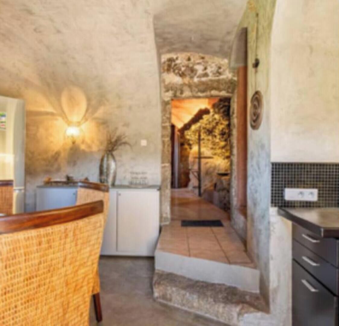 A kitchen with a stone wall, a wooden chair, and a small white refrigerator.