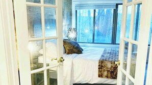 Une chambre à coucher avec un lit, des oreillers, une fenêtre et une vue sur les arbres.