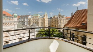 Un balcone con vista su edifici storici, tra cui facciate elaborate e una guglia di chiesa.