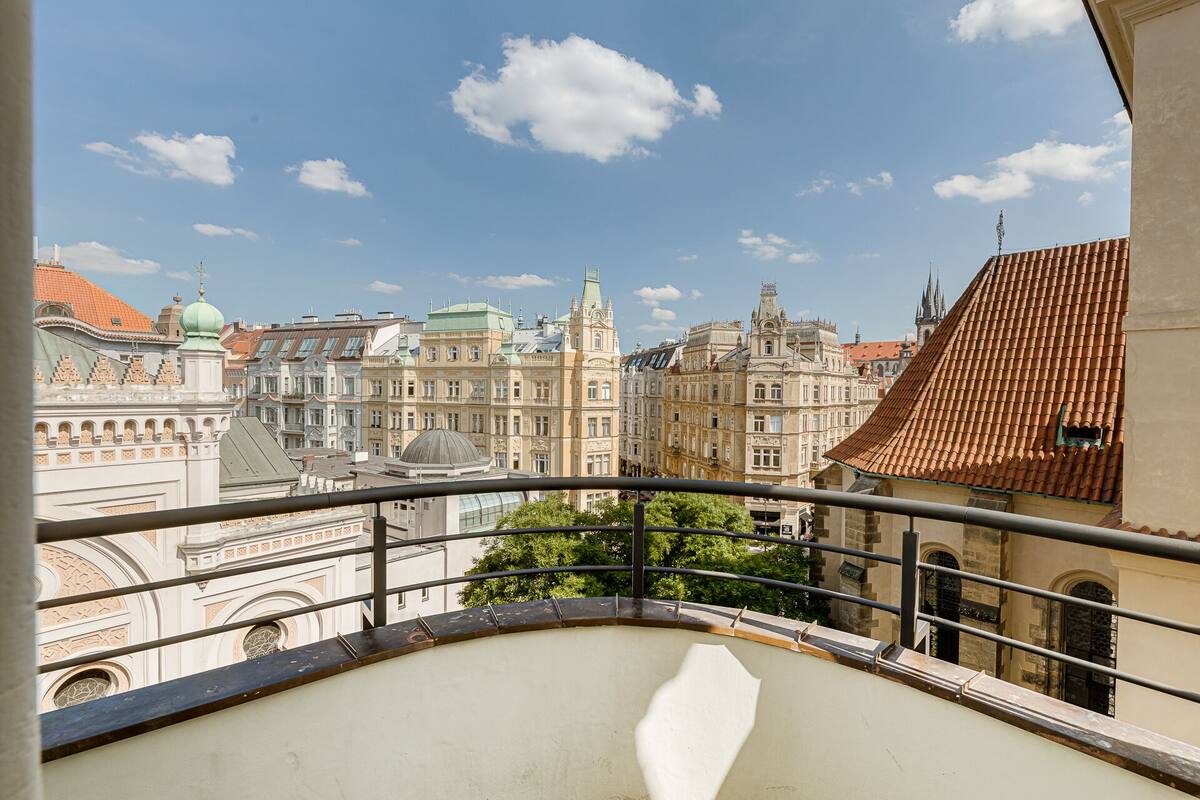 A balcony with a view of historic buildings, including ornate facades and a church spire.