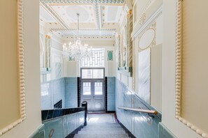 A grand hallway with a chandelier, ornate ceiling, and a door marked "EXIT". - G´Old Art Apartments (Prague)