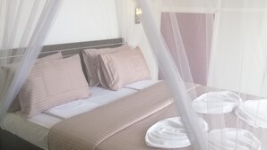 A bed with a canopy, pillows, and a bedside table with a white towel. - SunTop Inn (Ella)