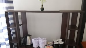 A kitchenette with a refrigerator, a coffee maker, a small sink, and a shelf with kitchen essentials. - SunTop Inn (Ella)