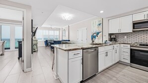 A modern kitchen with white cabinets, a stainless steel dishwasher, and a large island.