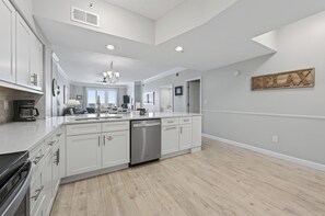 A modern kitchen with white cabinetry, a dishwasher, and a chandelier.