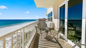 A balcony with a view of the beach, outdoor furniture, and a glass door leading to a room. - Inn at Crystal Beach 608a * Gulf Front with Beach Chair Set. Onsite dining! (Destin)