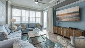 A living room with a gray sofa, a coffee table, and a large painting on the wall. - Inn at Crystal Beach 608 * Gulf Front with Beach Chair Set. Onsite dining! (Destin)