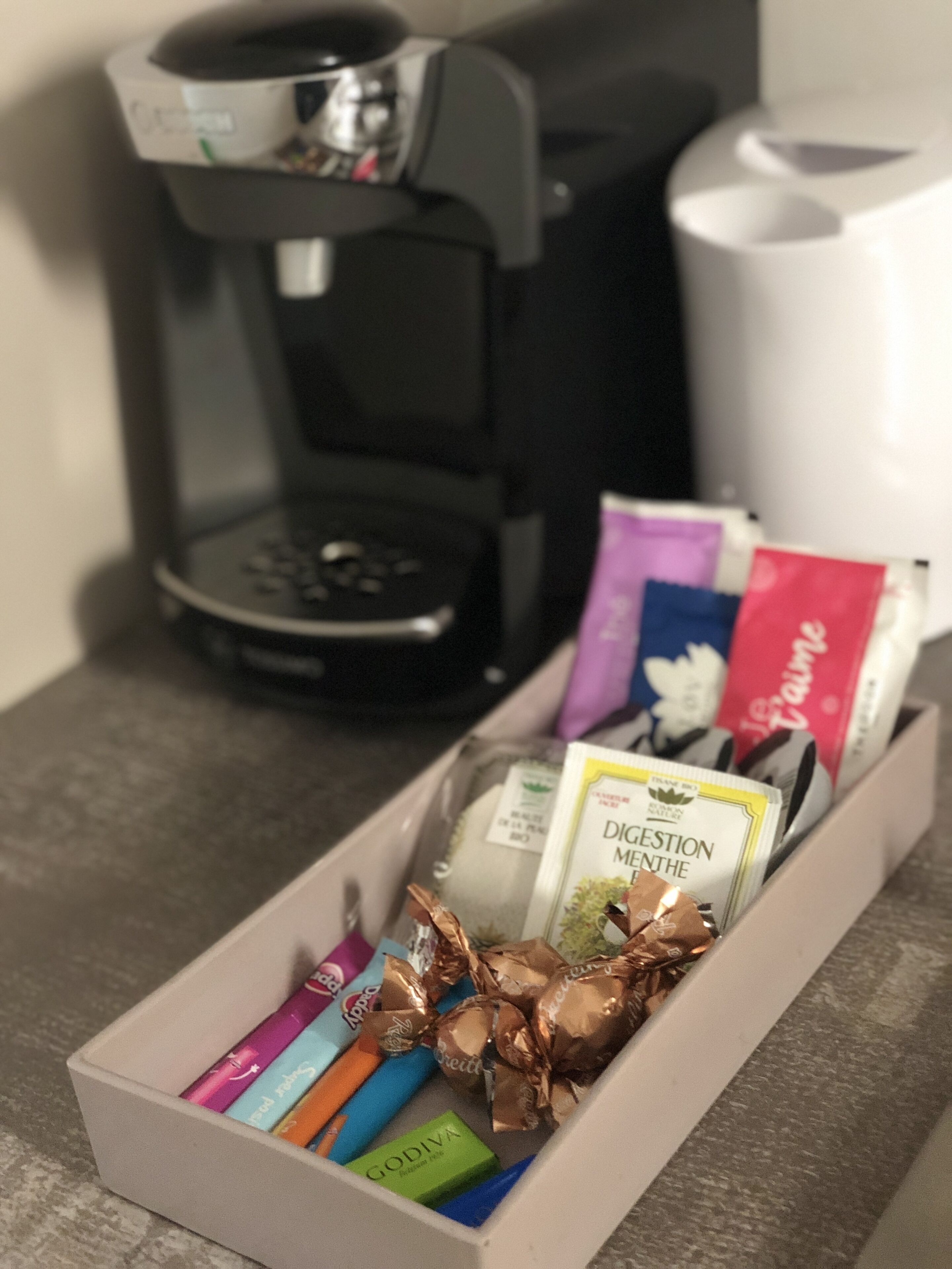 Een koffiezetapparaat, een prullenbak en een doos met diverse snacks.