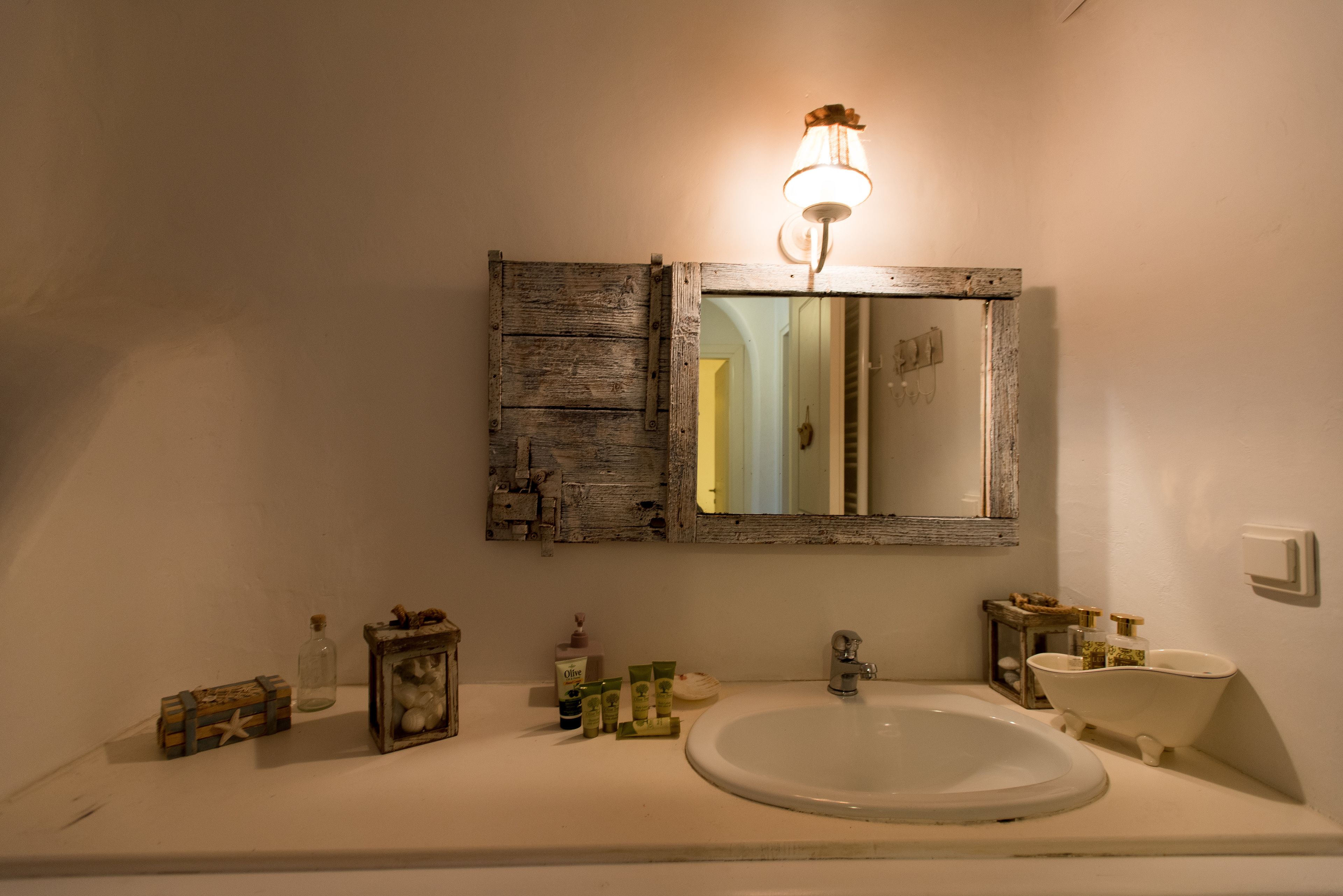 A bathroom with a rustic wooden mirror, a white sink, and a vintage-style bathtub.