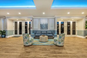 A spacious lobby with a blue sofa, two patterned armchairs, a woven coffee table, and a large abstract art piece above the sofa. - Inn at Crystal Beach 203 * July Early Booking Discounts (Destin)