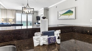 A hotel lobby with a marble reception desk, a chandelier, a framed fish artwork, and a variety of toiletries on the counter. - Inn at Crystal Beach 404 * Gulf Front with Beach Chair Set. Onsite dining! (Destin)