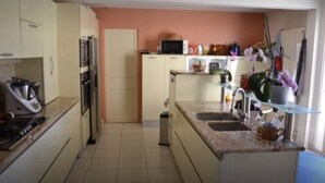 A compact kitchen with a microwave, stove, and sink. There is a door leading to another room, and a small trash bin is visible. - VILLA WITH GARDEN AND CLOSED SWIMMING POOL (Poulx)