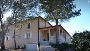 A two-story building with a front porch and a garage. - VILLA WITH GARDEN AND CLOSED SWIMMING POOL (Poulx)