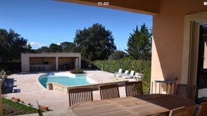 A patio with a pool, outdoor seating, and a covered area with a table and chairs. - VILLA WITH GARDEN AND CLOSED SWIMMING POOL (Poulx)
