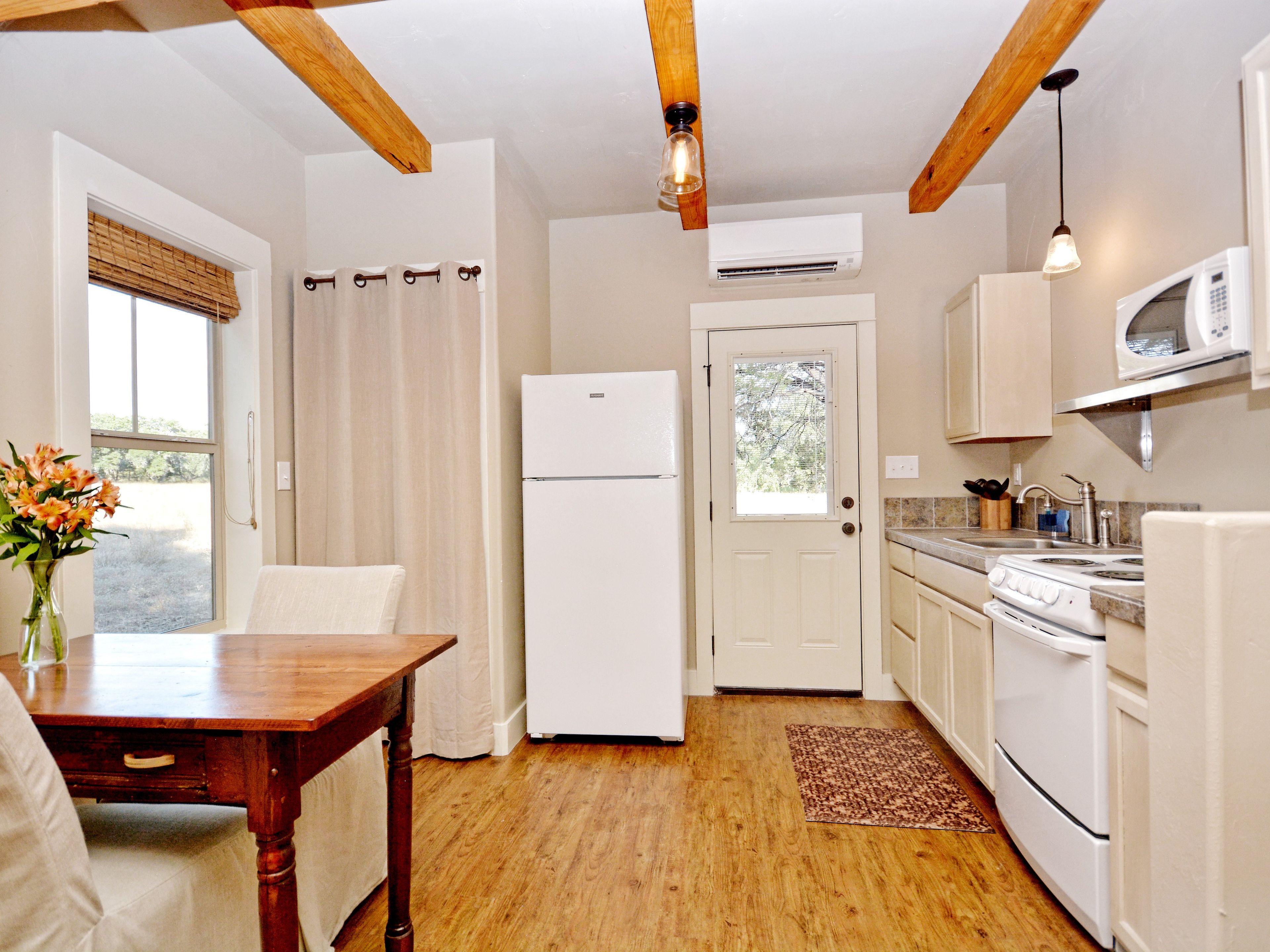 A kitchen with wooden beams, a white refrigerator, a stove, and a microwave.