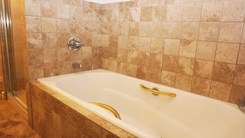 A bathroom with a bathtub, shower, and tiled walls.
