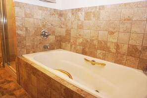 A bathroom with a bathtub, shower, and tiled walls.