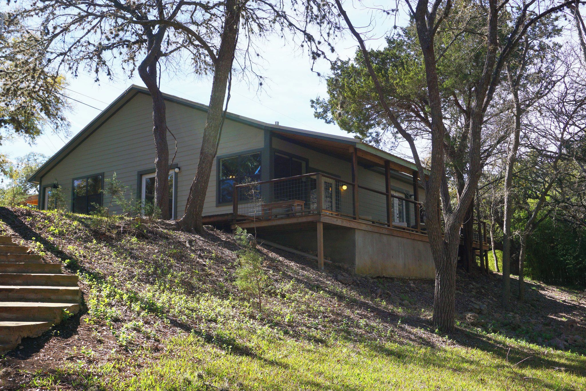 A modern house with a large deck and a staircase leading up to it.