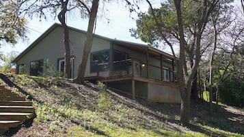 A modern house with a large deck and a staircase leading up to it.