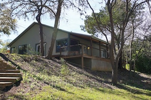 A modern house with a large deck and a staircase leading up to it.