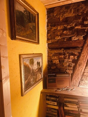 A room with a stone wall, a wooden staircase, and a bookshelf with books. - Apartment Vintage Home 55 (EA)