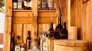 Un intérieur en bois avec des étagères où sont rangées diverses bouteilles, une horloge et des objets décoratifs.