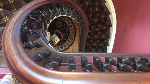 Eine Wendeltreppe mit hölzernem Geländer und aufwendigen Spindeln.