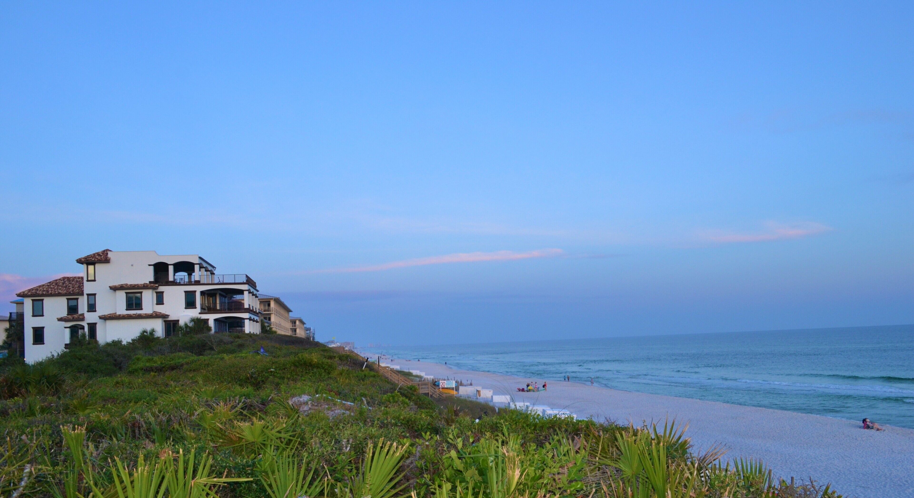 A beachfront property with a multi-story building, a sandy beach, and ocean views.