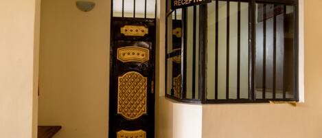 Una zona de recepción con una puerta de madera oscura con un diseño geométrico y un cartel arriba.