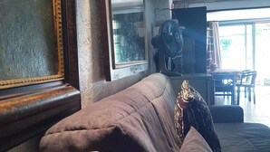 Una habitació amb una finestra gran, un sofà, un ventilador i una taula amb cadires.