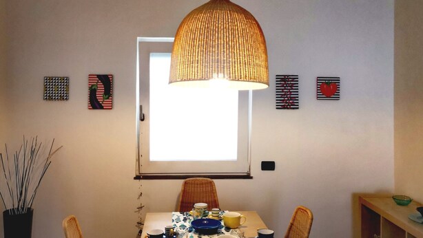 A dining area with a table set for two, a hanging lamp, and wall art. - Casa Zara Sorrento, the perfect apartment to discover the beauties of Sorrento (Sorrento)