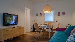 A modern living room with a television, a dining area, and a bed. - Casa Zara Sorrento, the perfect apartment to discover the beauties of Sorrento (Sorrento)