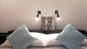 A bed with two patterned pillows, a wall-mounted sign with the text "PEACE LOVE & sandy feet," and two wall-mounted lights. - Casa Zara Sorrento, the perfect apartment to discover the beauties of Sorrento (Sorrento)