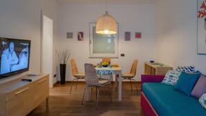 A modern living room with a television, dining table, chairs, and a sofa. - Casa Zara Sorrento, the perfect apartment to discover the beauties of Sorrento (Sorrento)