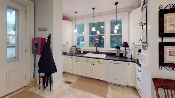 Una cocina con armarios blancos, encimera negra, ventana decorada con una estrella y un electrodoméstico rojo.