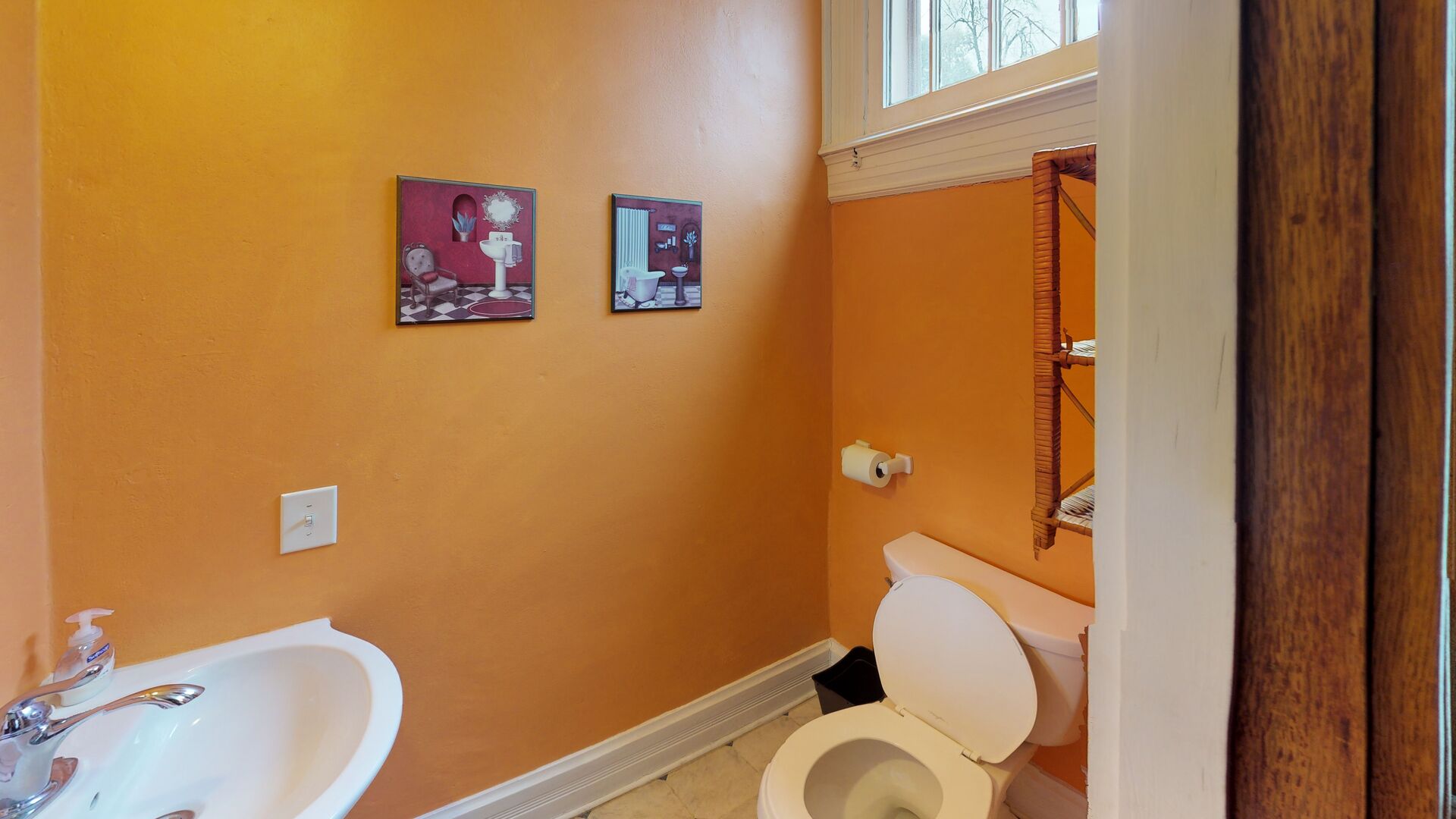 A bathroom with a white bathtub, a toilet, and two wall-mounted pictures.