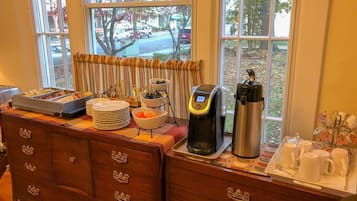A breakfast bar with a coffee maker, a thermos, and a mug holder.