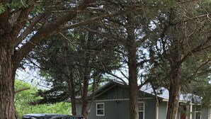 A dark-colored SUV parked on a gravel driveway in front of a house with a porch and a small table. - Lake Texoma! Beautiful Cabin with Relaxing atmosphere!sleeps 5 (Gordonville)